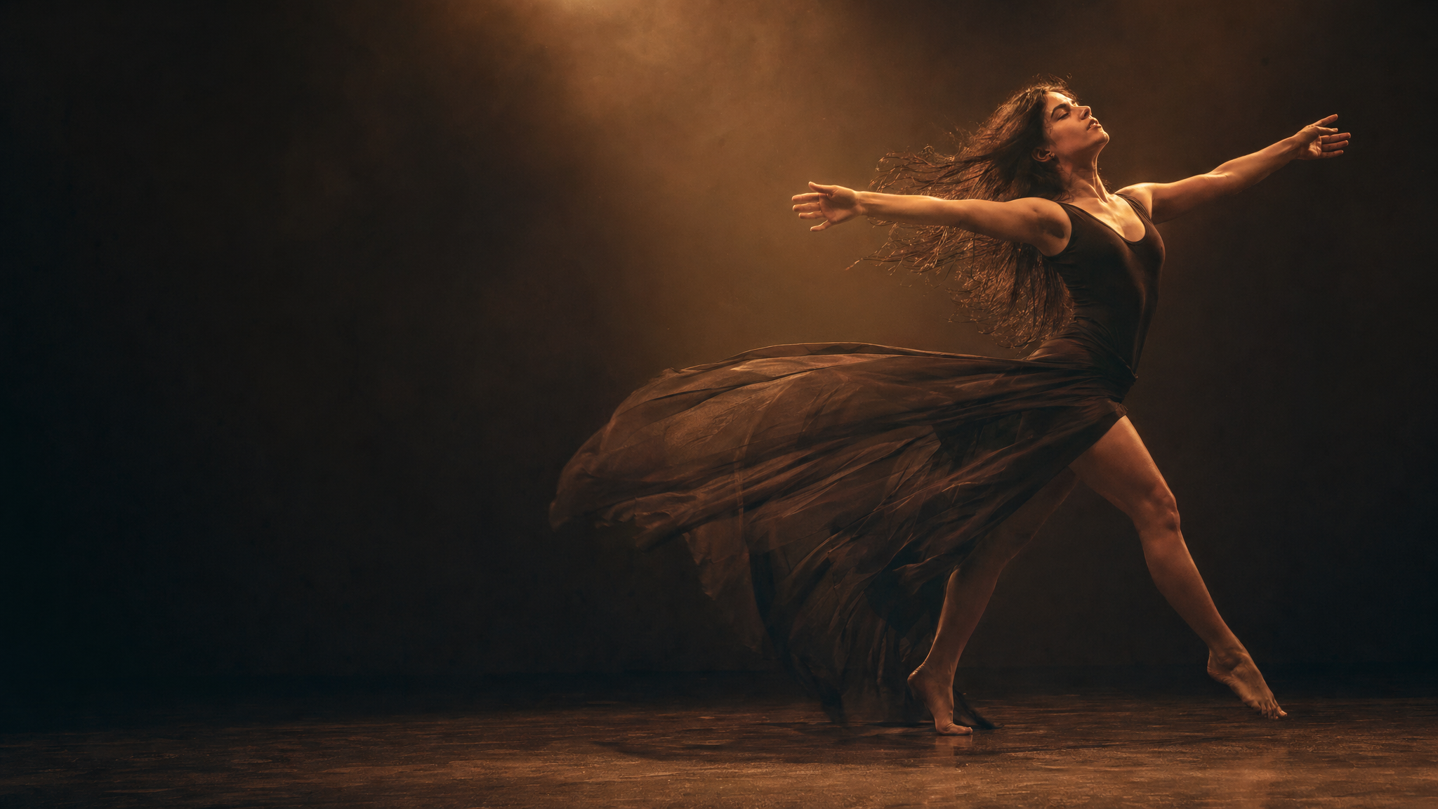 Contemporary dancer in expressive floor-to-air movement, warm stage lighting