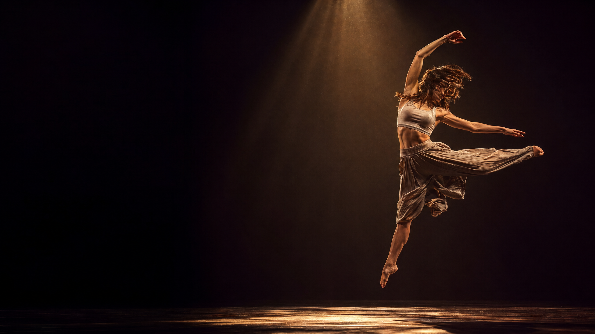 Professional dancer mid-leap in dramatic spotlight